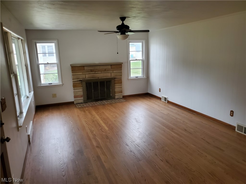 5530 Manchester Road Akron, OH 44319 - Photo 5 of 24 Unfurnished living room with a healthy amount of sunlight, hardwood / wood-style flooring, a fireplace, and ceiling fan