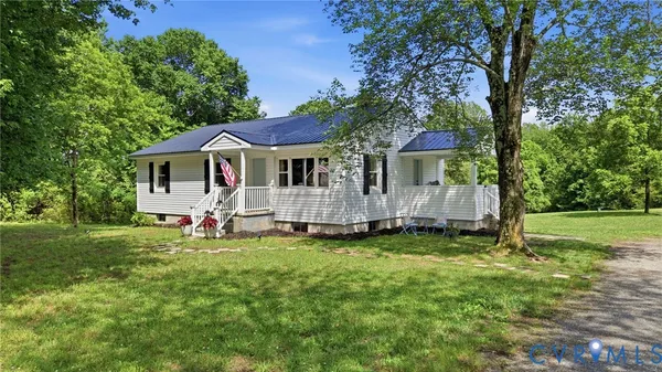 a white house with a big yard and large trees
