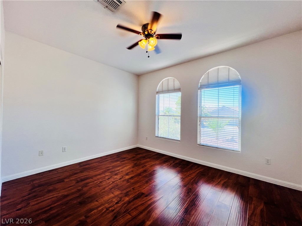 3047 Hickory Valley Road Henderson, NV 89052 - Photo 21 of 33 Rich hardwood floors complement a bedroom well-lit by two arched windows.