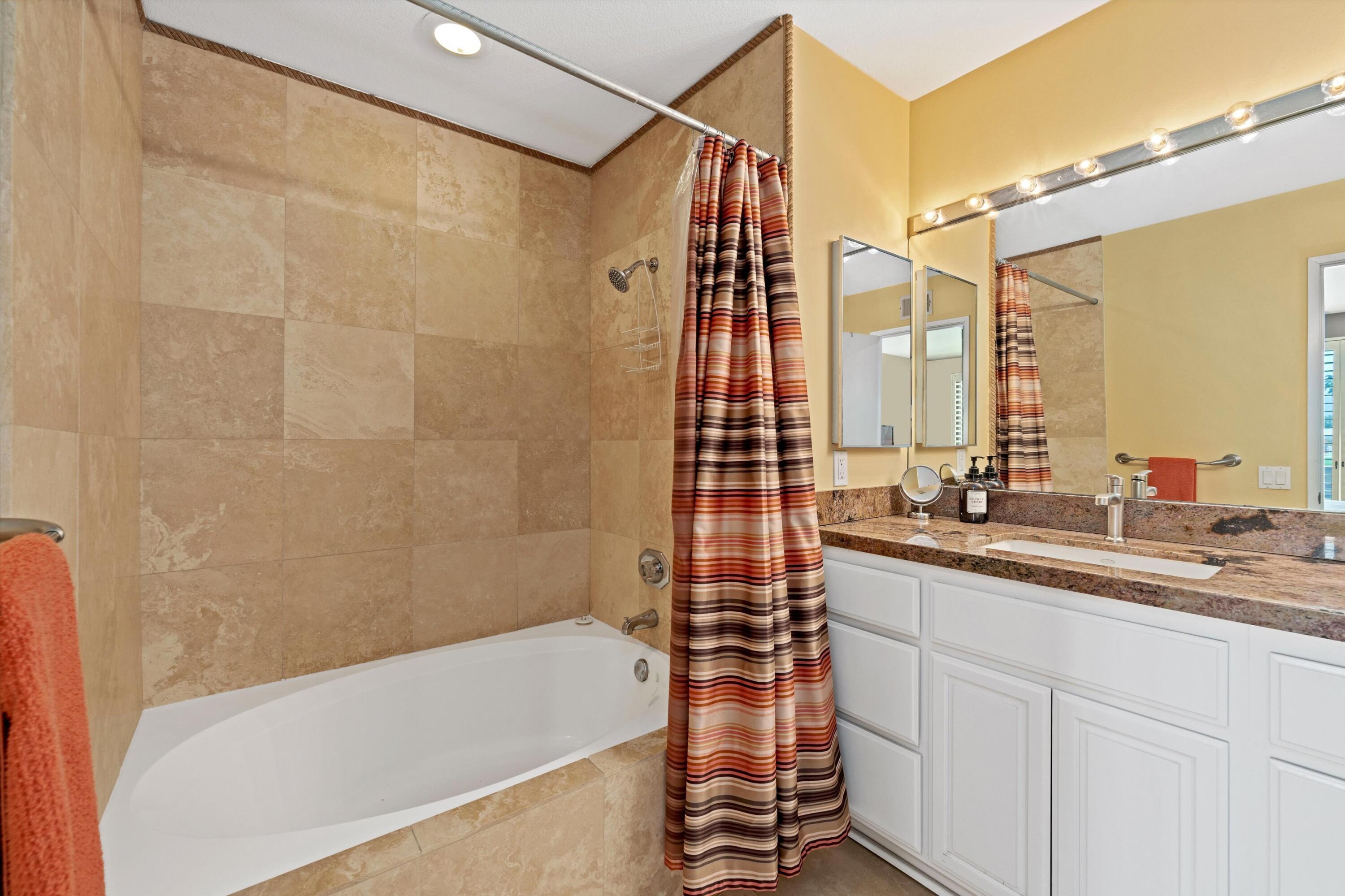 54053 Oak-Hill La Quinta, CA 92253 - Photo 18 of 36 a bathroom with a double vanity sink a mirror and a bathtub