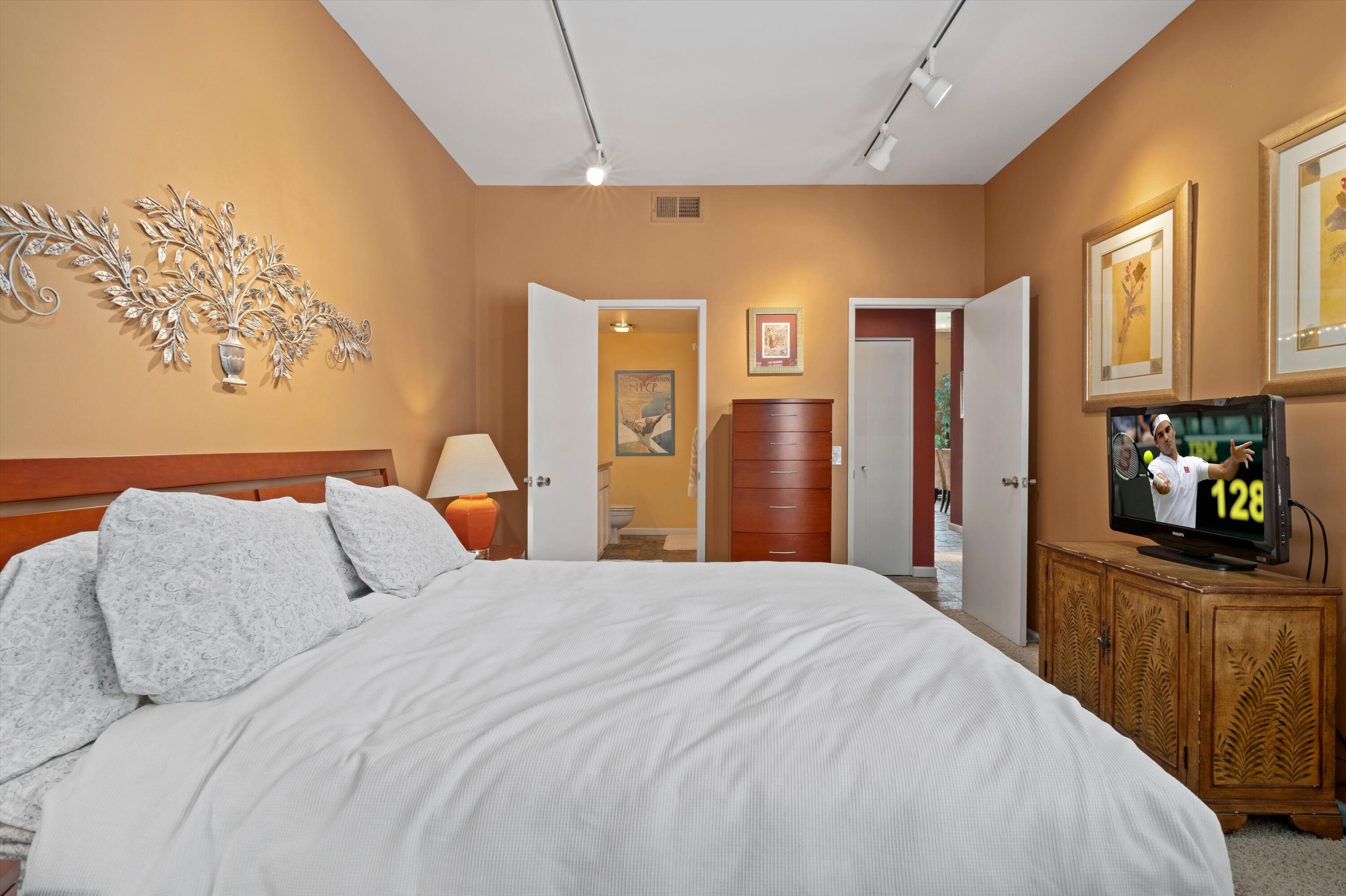 54053 Oak-Hill La Quinta, CA 92253 - Photo 20 of 36 a bedroom with a large bed and a flat tv screen on dresser