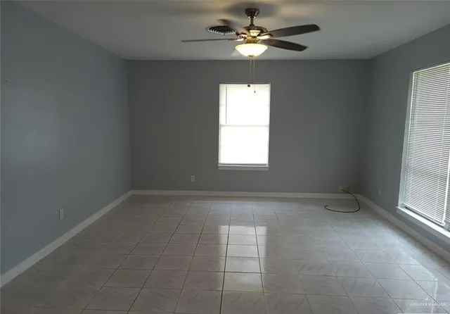 an empty room with windows and fan