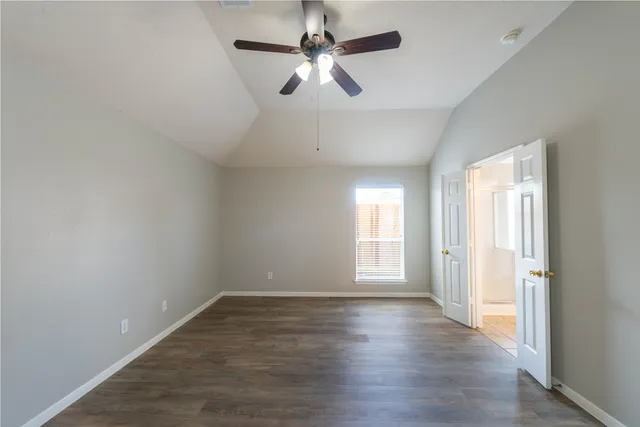an empty room with wooden floor ceiling fan and windows