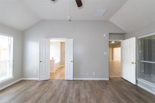 an empty room with wooden floor and windows