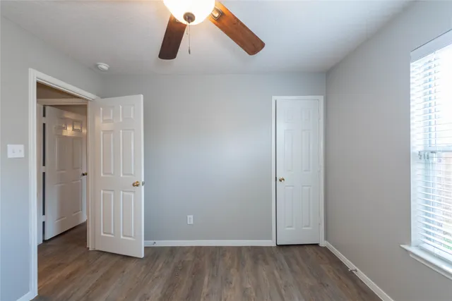 an empty room with wooden floor cabinet and windows