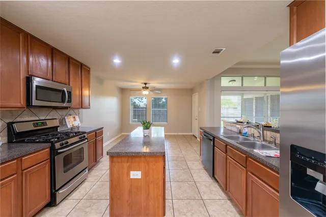 a kitchen with granite countertop stainless steel appliances a sink stove and cabinets