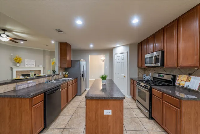a kitchen with stainless steel appliances granite countertop wooden cabinets a stove top oven and granite counter tops