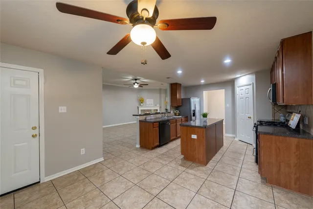 a large kitchen with stainless steel appliances kitchen island granite countertop a refrigerator and a stove top oven