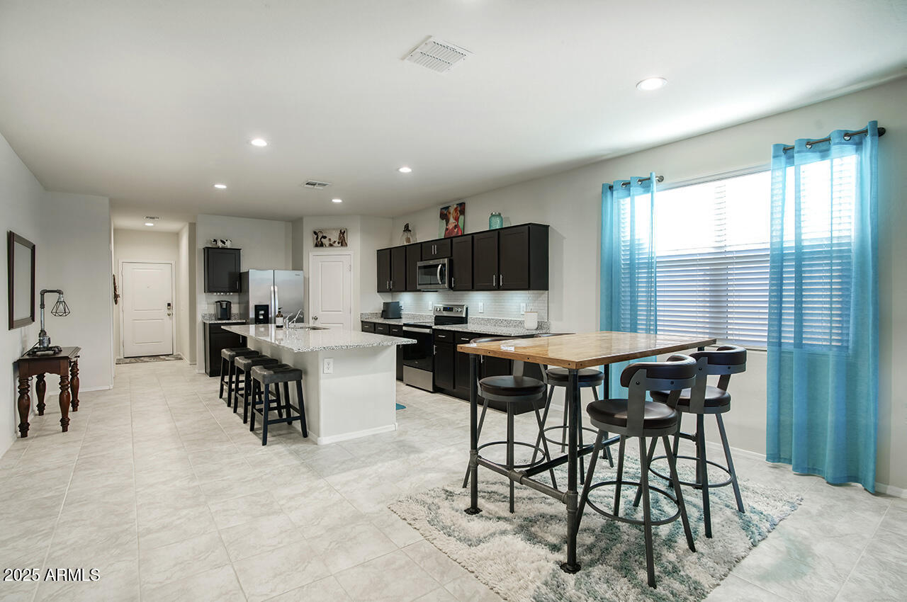 5236 East Emery Road San Tan Valley, AZ 85143 - Photo 8 of 24 a kitchen with stainless steel appliances kitchen island granite countertop a table chairs sink and cabinets