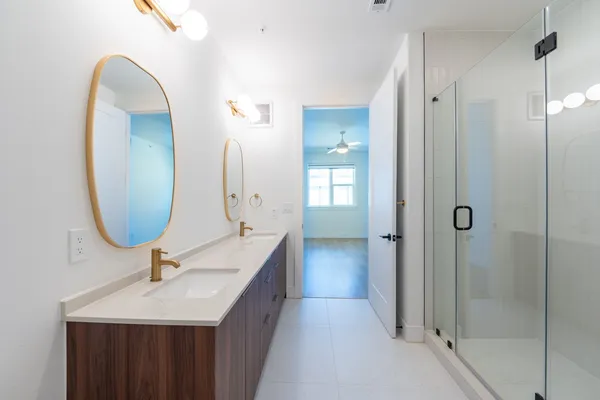 a bathroom with a double vanity sink mirror and shower
