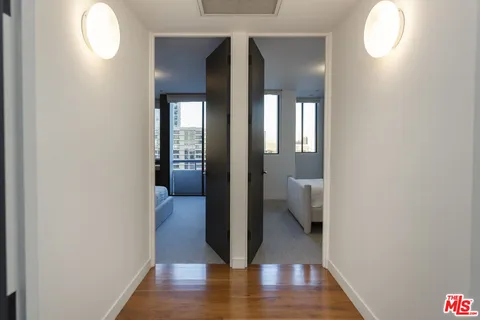 a view of a hallway with wooden floor and a bathroom
