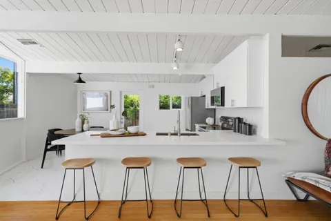 a kitchen with stainless steel appliances kitchen island granite countertop a dining table chairs and a refrigerator