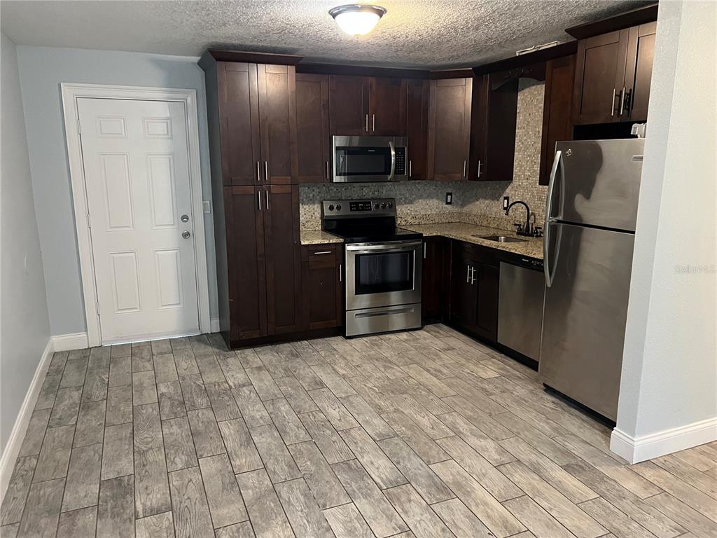 920 Maydell Drive, Unit B Tampa, FL 33619 - Photo 2 of 7 a kitchen with stainless steel appliances granite countertop a refrigerator a stove top oven a sink and dishwasher