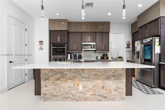 a large kitchen with granite countertop a large counter top stainless steel appliances and cabinets