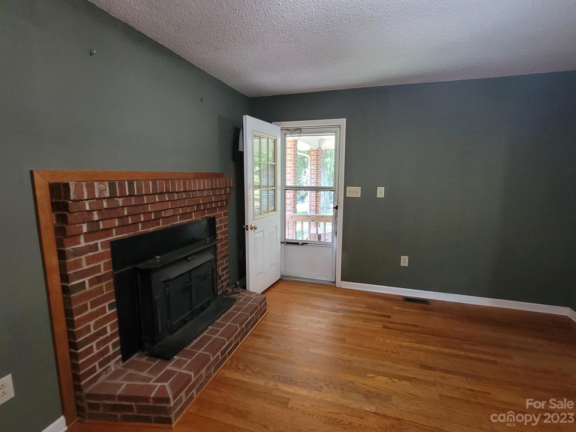 818 St Marks Church Road Bessemer City, NC 28016 - Photo 31 of 48 an empty room with wooden floor fireplace and windows