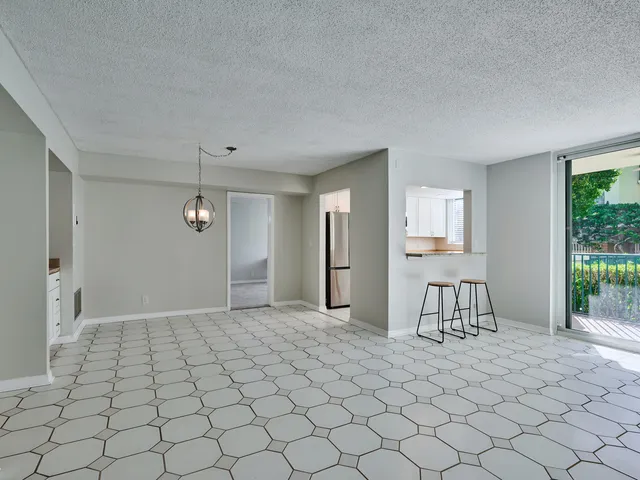 a view of an empty room with window and chandelier