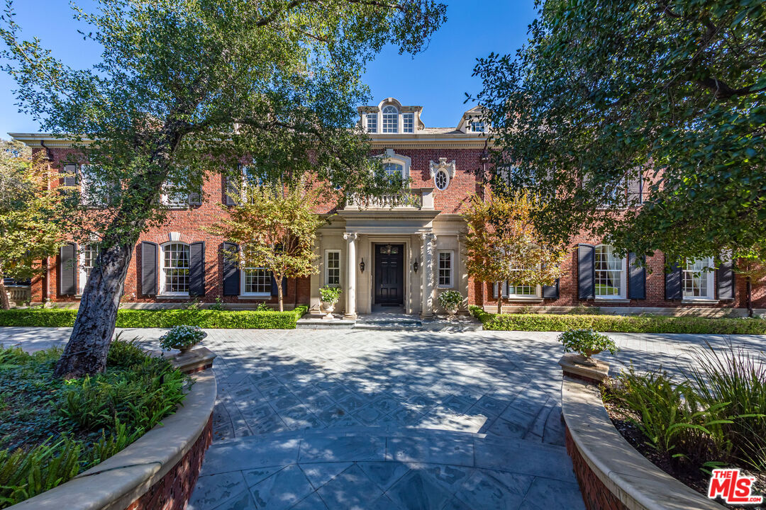a front view of a house with garden and trees