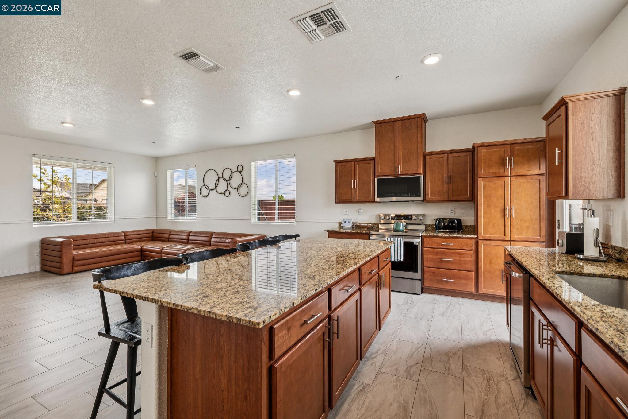 4748 Beacon Way Rio Vista, CA 94571 - Photo 12 of 35 a kitchen with stainless steel appliances granite countertop a stove top oven a sink dishwasher a dining table and chairs with wooden floor