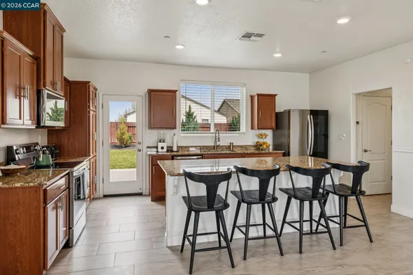 a kitchen with stainless steel appliances granite countertop table chairs sink and cabinets
