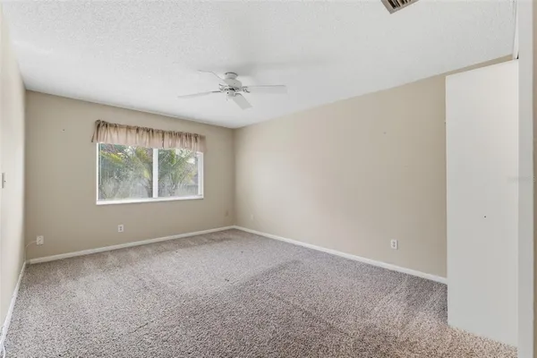 an empty room with a ceiling fan and a window