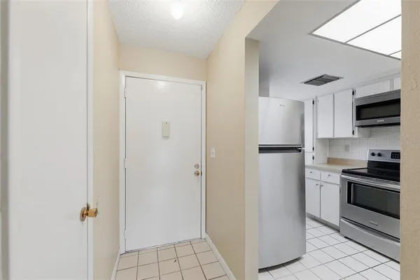 a kitchen with stainless steel appliances granite countertop a refrigerator a stove a sink a microwave oven with white cabinets