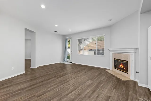 an empty room with wooden floor fireplace and windows