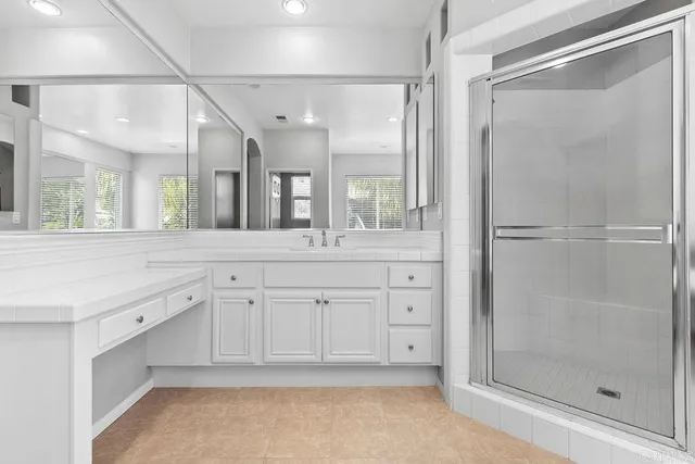 a spacious bathroom with a shower a sink and a mirror