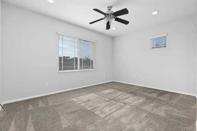 an empty room with windows and ceiling fan