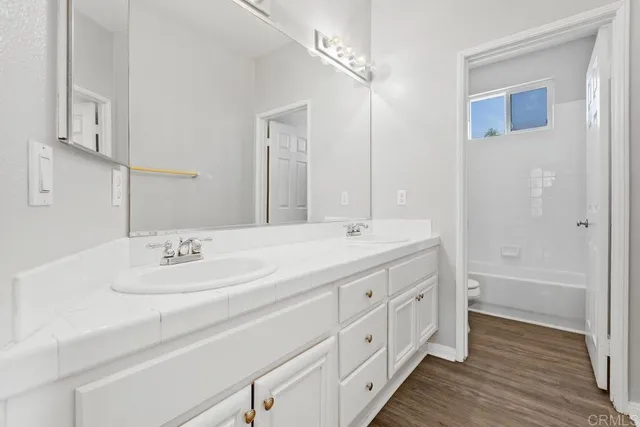 a bathroom with a double vanity sink a mirror and a bathtub