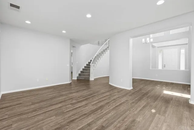 a view of an empty room with wooden floor and stairs
