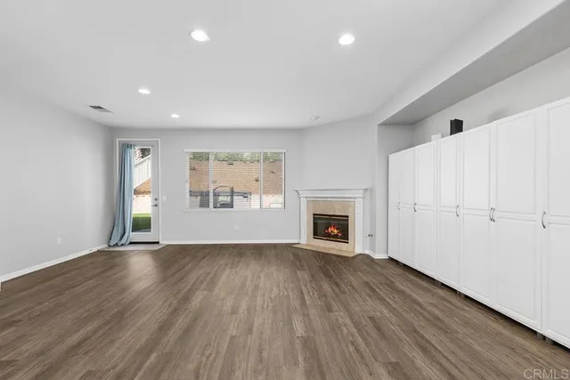 an empty room with wooden floor fireplace and windows