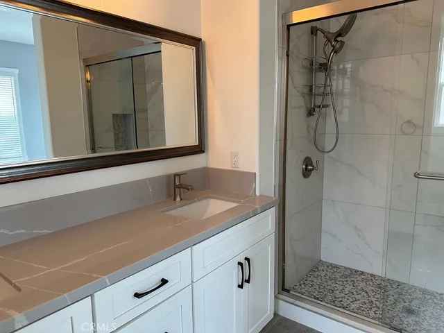 a bathroom with a granite countertop sink a mirror and shower