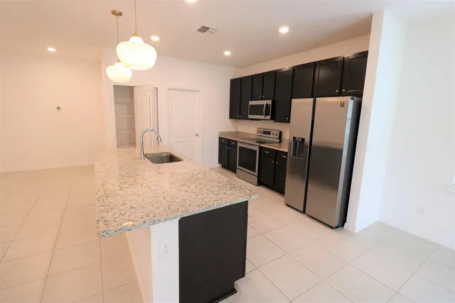 a kitchen with stainless steel appliances granite countertop a refrigerator a sink a stove a microwave and island