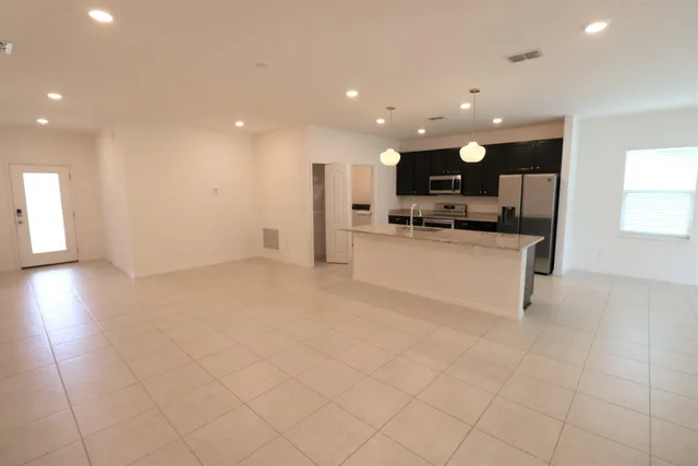 a view of open kitchen with kitchen island granite countertop a sink and a stove top oven
