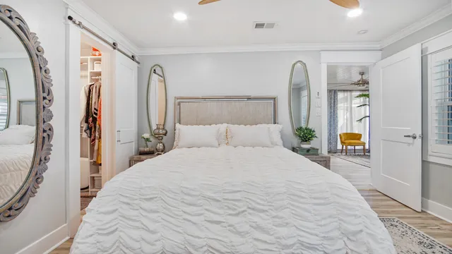 a large white bed in a white bedroom next to a window