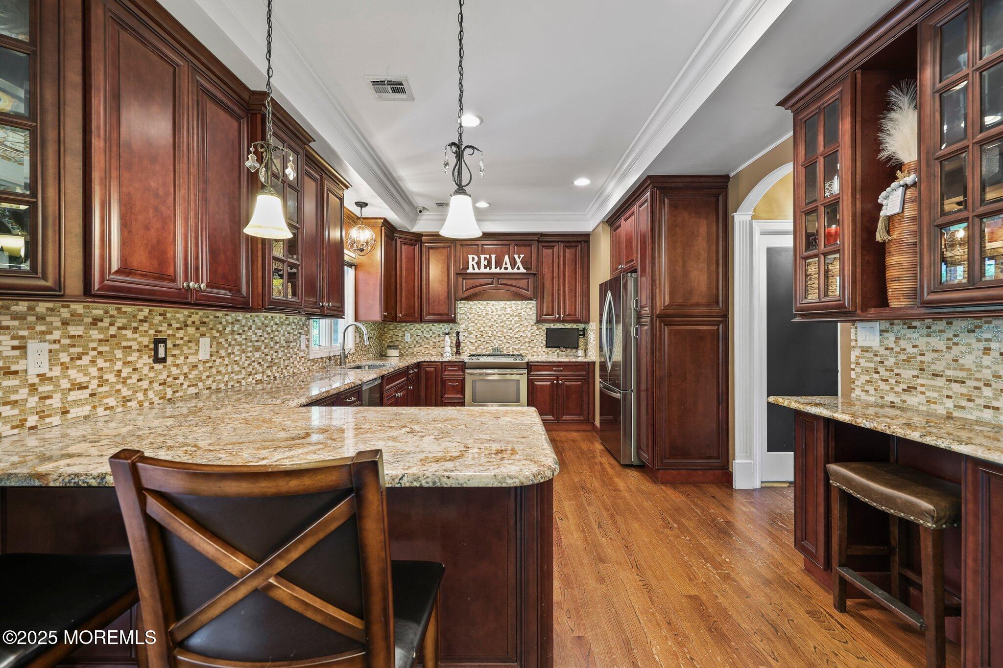 4 White Pines Way Freehold, NJ 07728 - Photo 14 of 66 a kitchen with stainless steel appliances granite countertop a stove a refrigerator a oven a sink a dining table and chairs with wooden floor