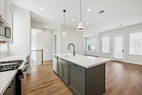 a large kitchen with a large counter top a sink stainless steel appliances and cabinets