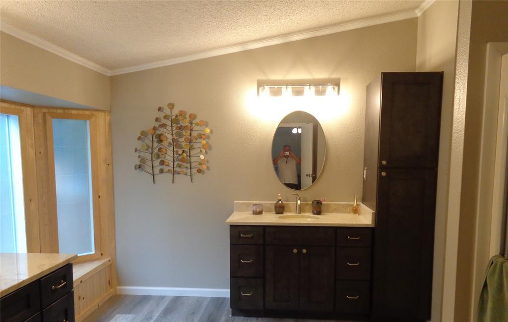 5525 Cedar Oaks Road Grandview, TX 76050 - Photo 17 of 40 Dark wood-finish vanity with a light countertop and oval mirror, complemented by a tall storage cabinet