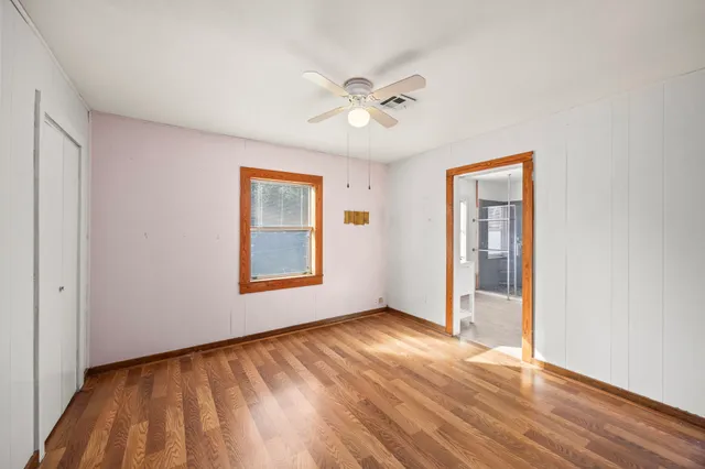 a view of an empty room with window and wooden floor