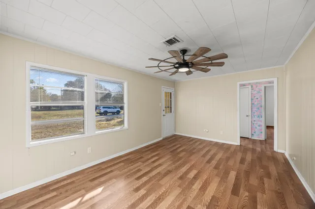 a view of empty room with wooden floor and fan