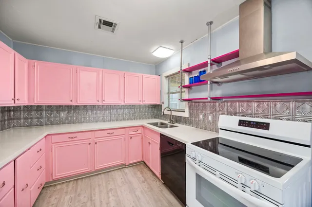 a kitchen with a sink dishwasher and a stove with wooden floor