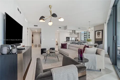 a living room with furniture a flat screen tv and kitchen view