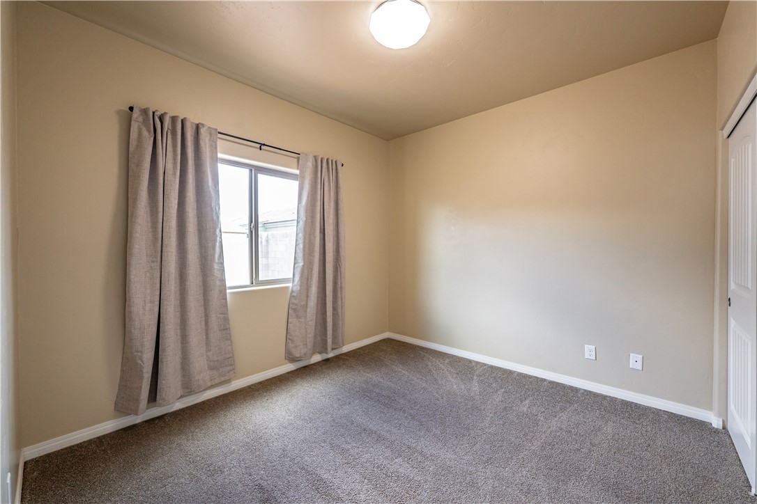 3546 North Kenneth Road Kingman, AZ 86409 - Photo 20 of 35 The room features neutral-toned walls, a window with curtains, and carpeted flooring