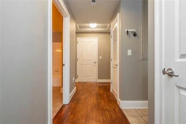 a view of a hallway with wooden floor and a bathroom
