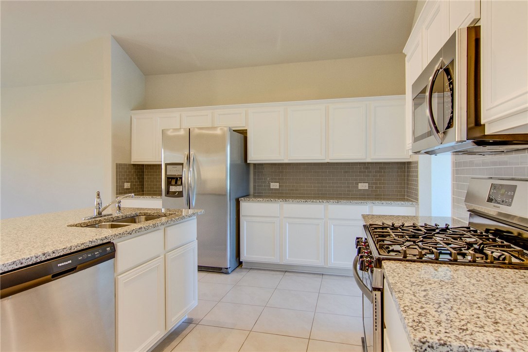 7012 Ranchito Drive Austin, TX 78744 - Photo 13 of 34 a kitchen with stainless steel appliances granite countertop a stove a sink and a refrigerator