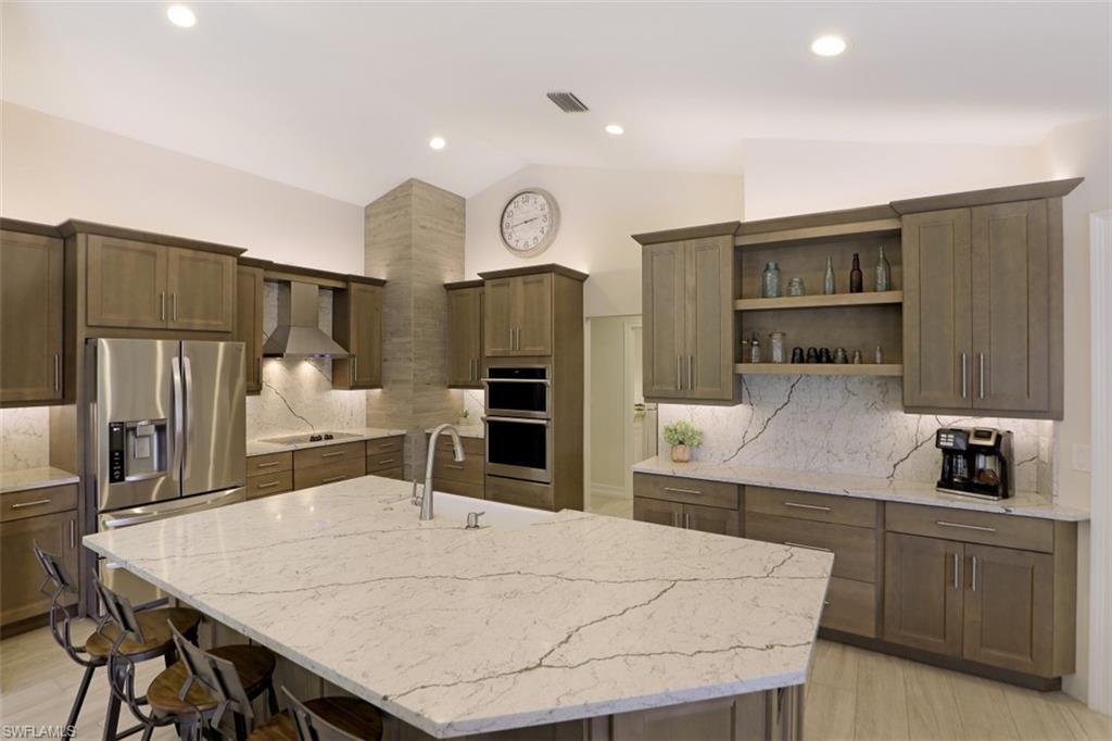 471 Ibis Way Naples, FL 34110 - Photo 2 of 32 a kitchen with stainless steel appliances kitchen island granite countertop a table chairs microwave and sink