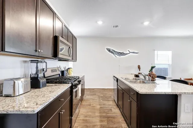 a kitchen with stainless steel appliances granite countertop a sink stove and cabinets
