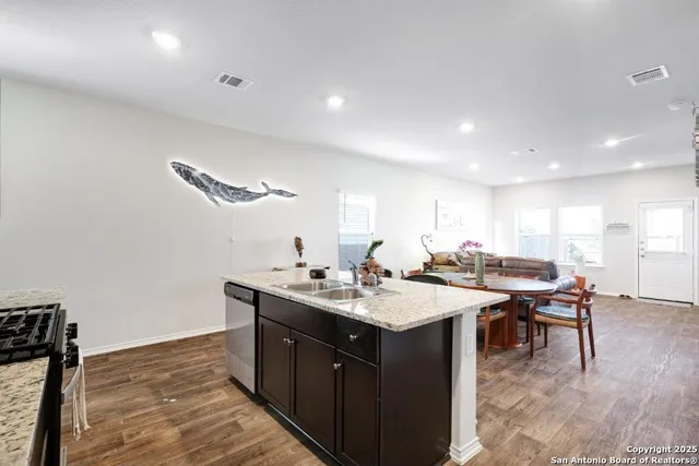 a kitchen with a stove a sink a dining table and chairs with wooden floor