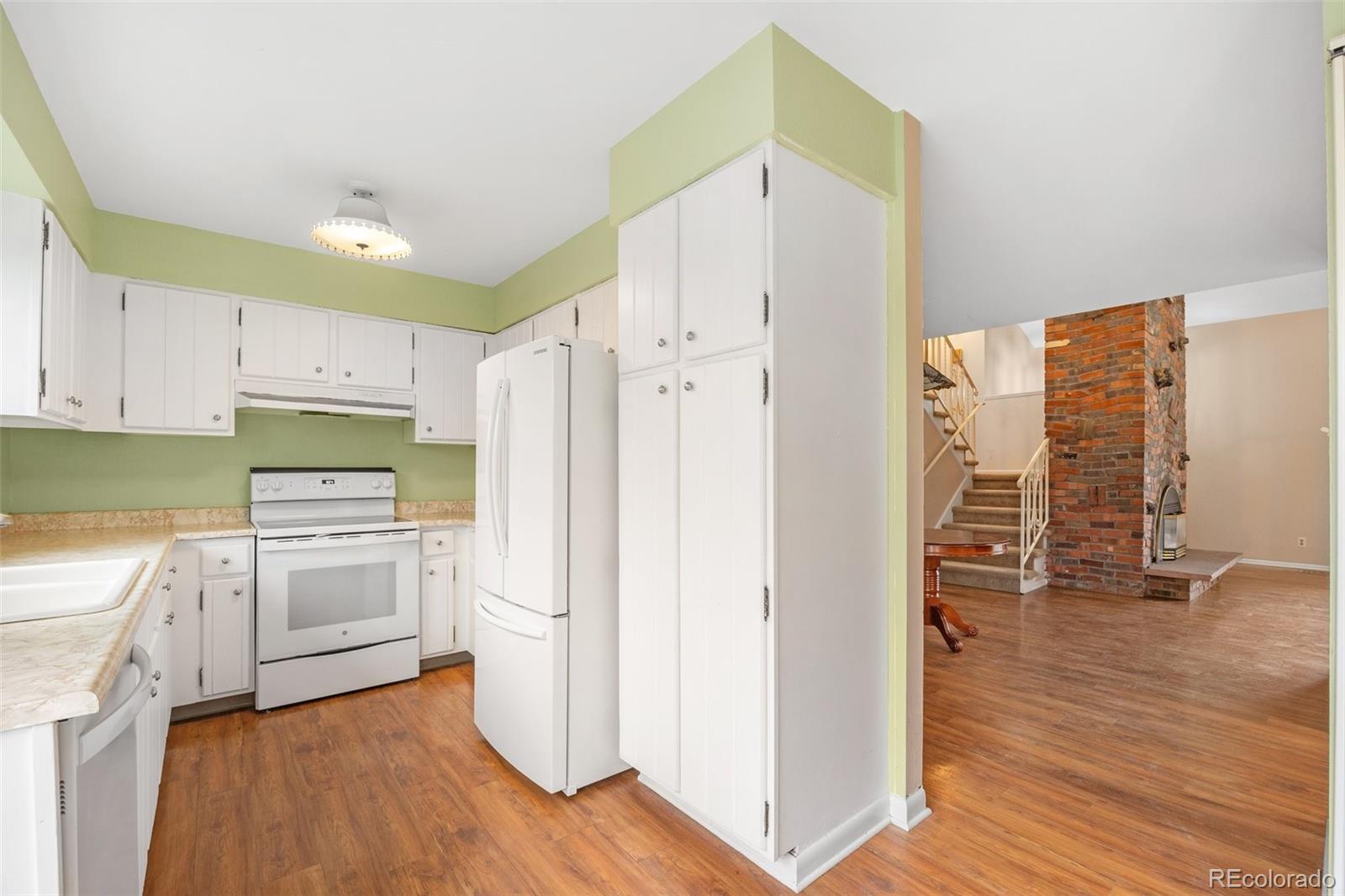 6495 East Happy Canyon Road, Unit 171 Denver, CO 80237 - Photo 6 of 27 a kitchen with granite countertop a refrigerator a sink dishwasher and a stove with wooden floor
