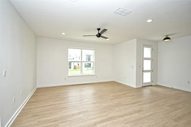 an empty room with wooden floor and windows